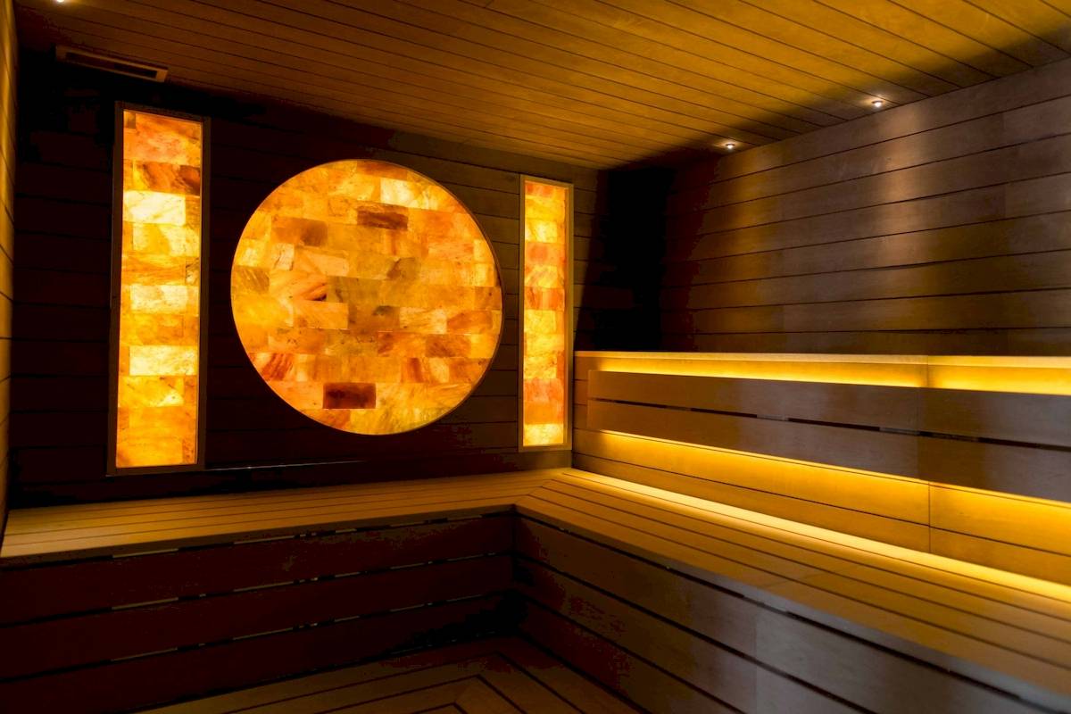 Innenansicht der Sauna von L'Hostellerie du Moulin mit gelben Lichtern und Holzwänden.