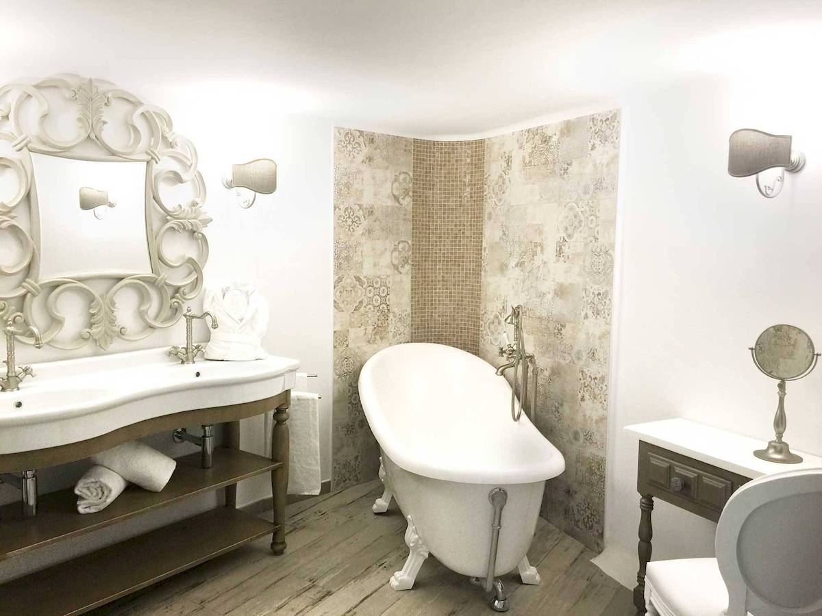 Badezimmer in L'Hostellerie du Moulin mit Badewanne, Waschbecken und dekorativen Wandfliesen.