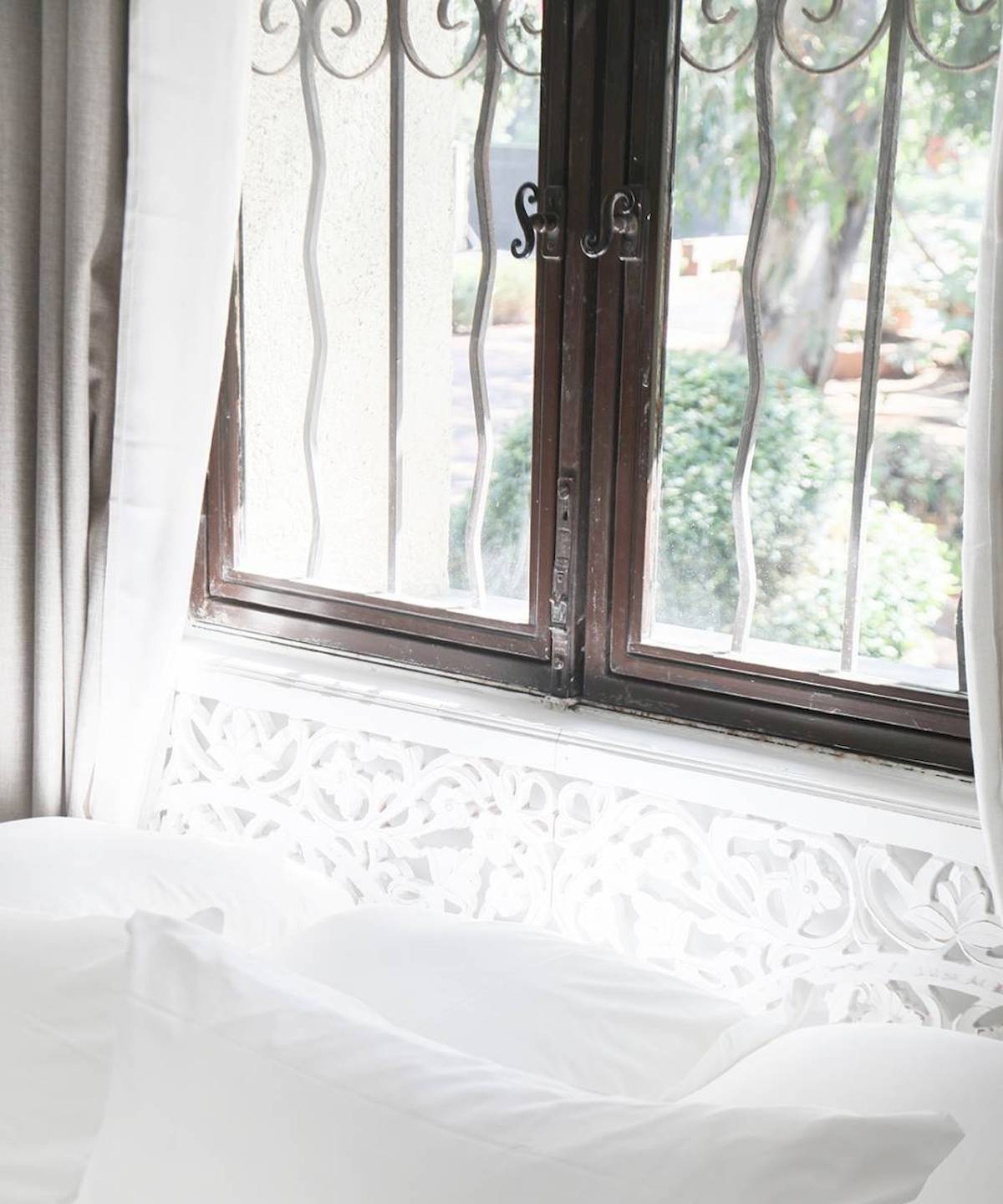 Ein Bett mit weißen Kissen und einem Fenster im Hintergrund im Hotel L'Hostellerie du Moulin