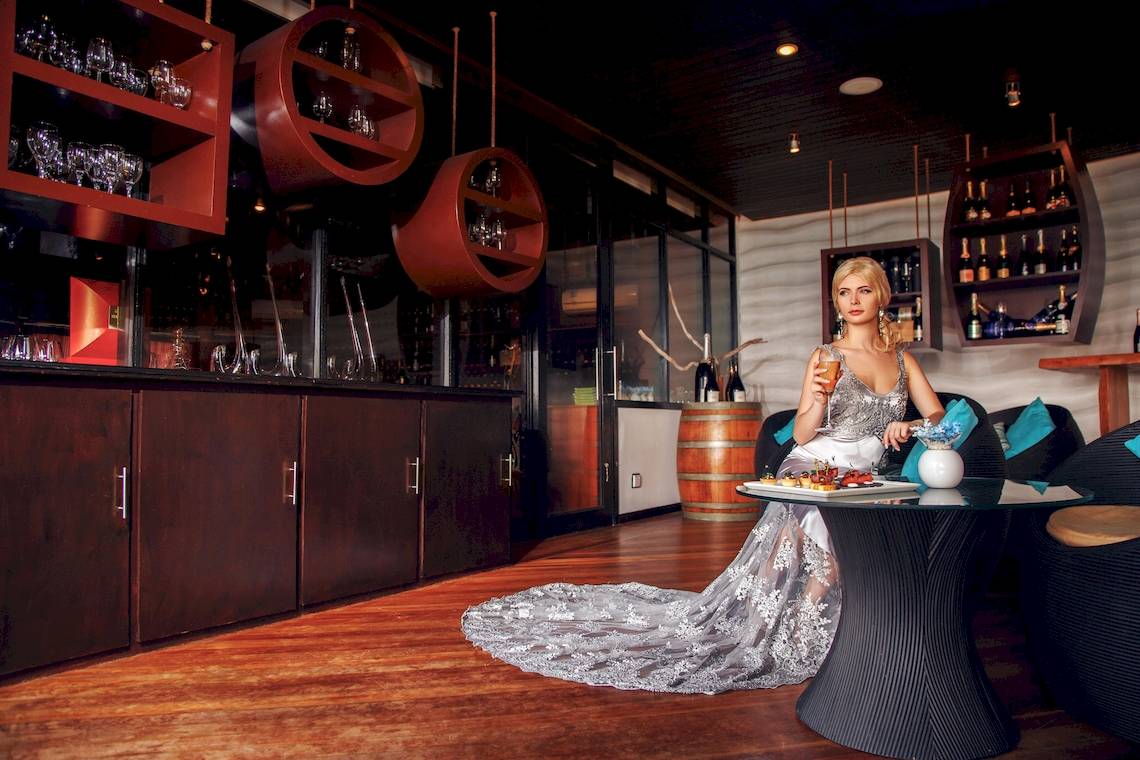 Eine Braut im Kleid sitzt an einem Tisch in einer Bar des Sun Siyam Iru Fushi Hotels.