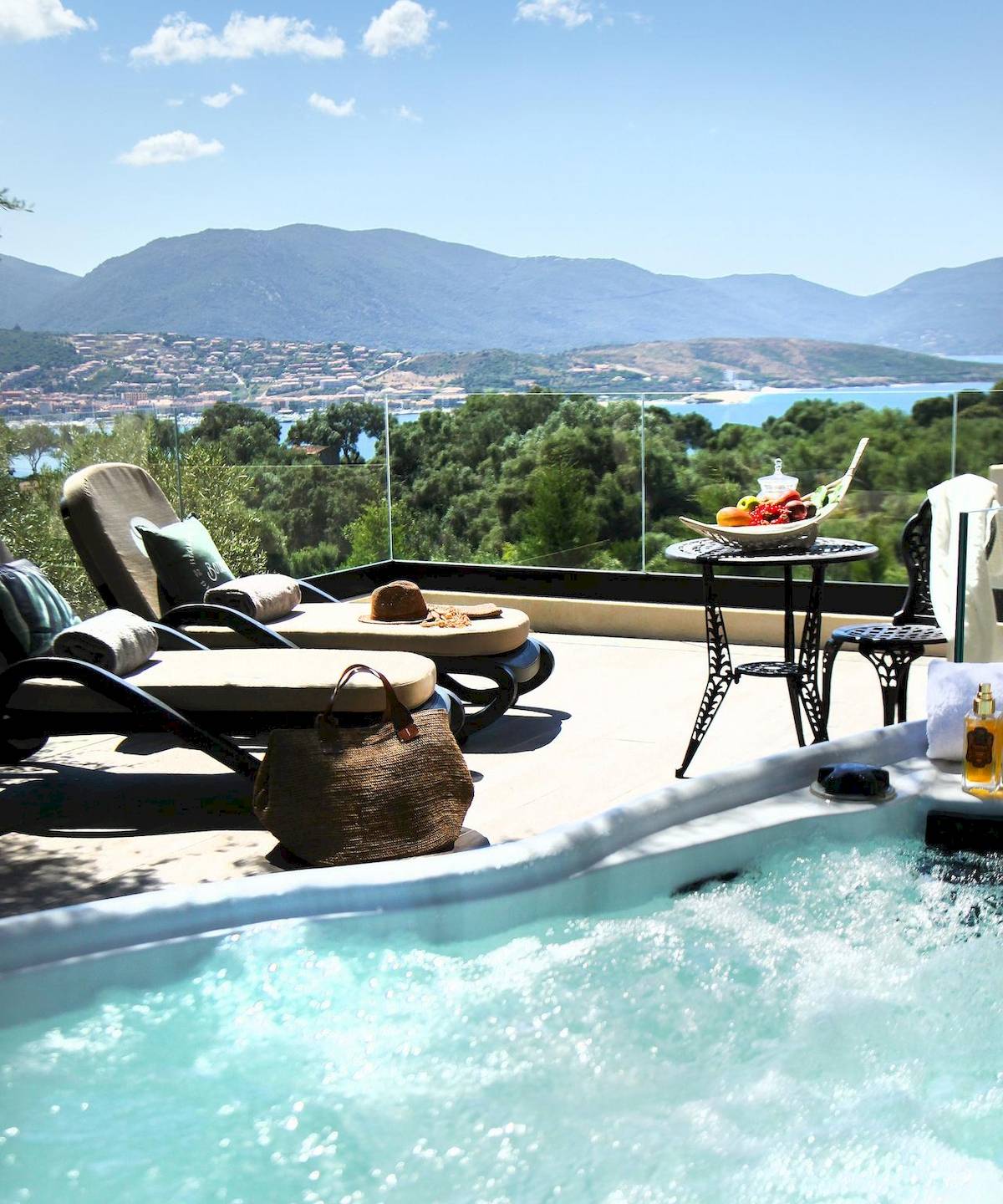 Außenbereich mit Blick auf das Meer, Lounge-Liegesesseln und einem Whirlpool.