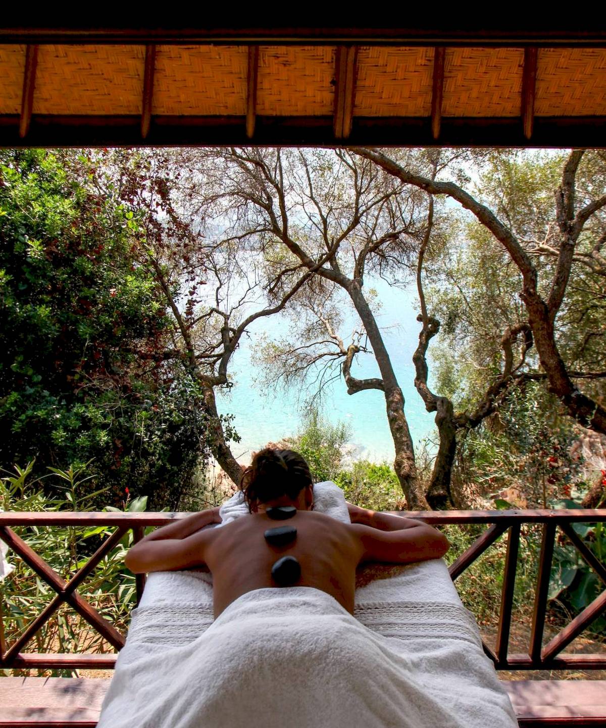 Massage auf Holzterrasse im L'Hostellerie du Moulin mit Blick auf Bäume und Meer