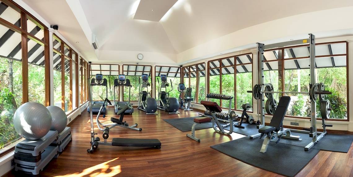 Fitnesscenter im Hotel Sun Siyam Iru Fushi mit Geräten und Blick auf den Garten.