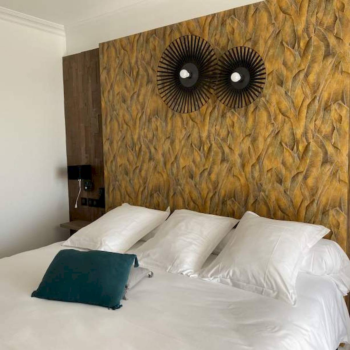 La Lagune Hotelzimmer mit blauem Kissen auf weißem Bett und dekorativer Wand