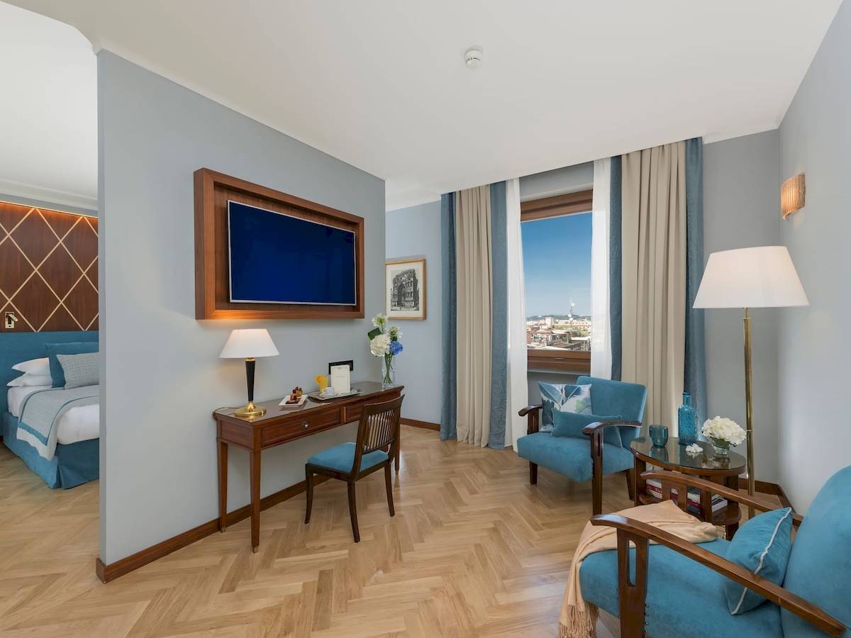 Innenansicht eines Zimmers im Bettoja Hotel Mediterraneo mit Schreibtisch, Fernseher und Fenster mit Stadtblick.