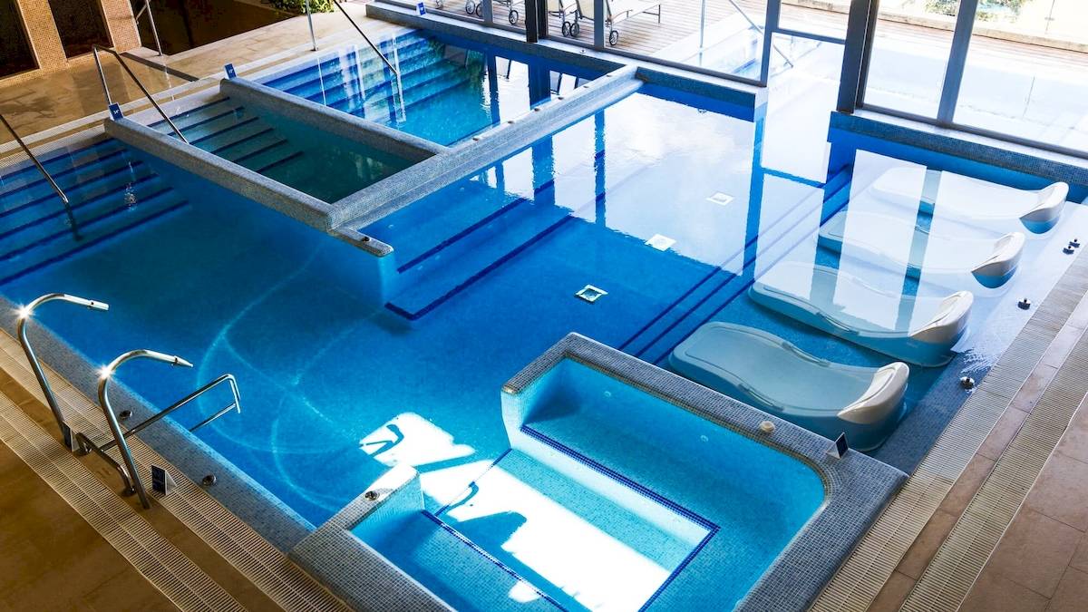 Ein modernes Schwimmbad im ARTIEM Audax Hotel mit separaten Bereichen und Liegestühlen.