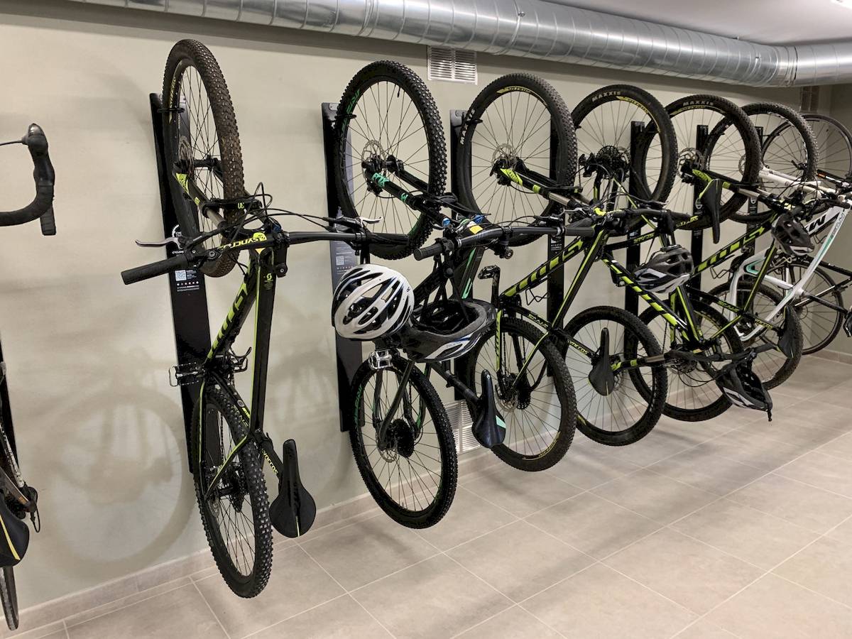 Fahrräder sind in einer Reihe in einer Garage aufgehängt, darunter ein Fahrrad mit Helm, das an einem schwarzen Ständer befestigt ist.