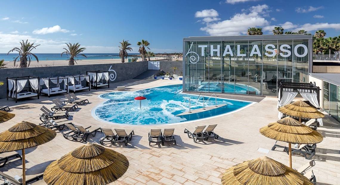 Außenbereich des Barcelo Fuerteventura Castillo mit Pool und Sonnenliegen am Strand.
