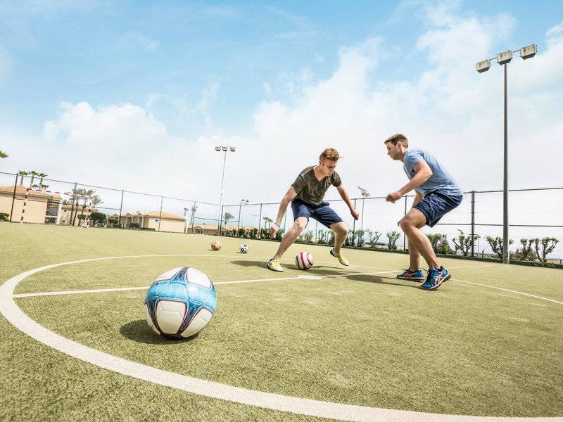 Zwei Männer spielen Fußball auf einem Feld im Punta Prima Resort & Spa.