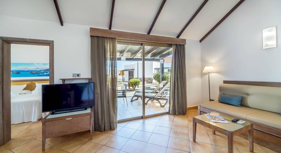 Innenansicht eines Hotelzimmers mit Bett, Fernseher und Balkon.