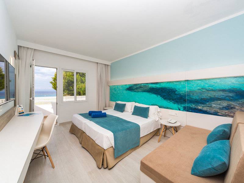 Innenansicht eines Zimmers im Globales Lord Nelson Hotel mit einem großen Bett und einem Ausblick auf das Meer.
