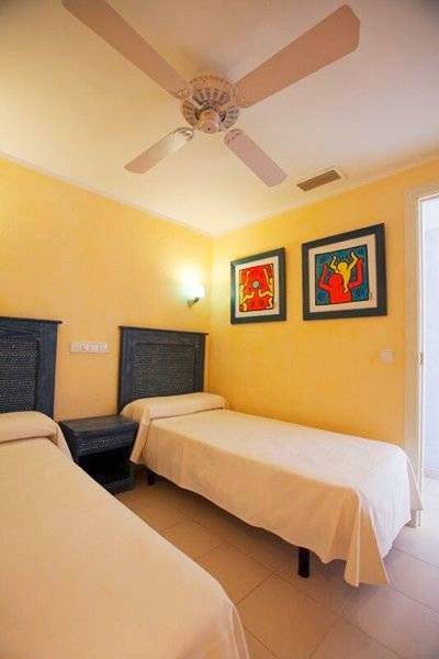 Doppelzimmer im Royal Son Bou Family Club mit zwei Betten, Deckenventilator und farbenfrohen Wänden.