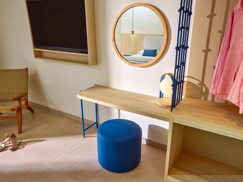 Inneneinrichtung eines Zimmers im Victoria Menorca Hotel mit Schreibtisch, Spiegel, Fernseher und Bett.