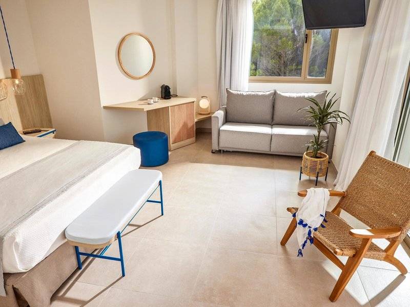 Victoria Menorca Hotelzimmer mit Doppelbett, Couch, Tisch und Fenster.