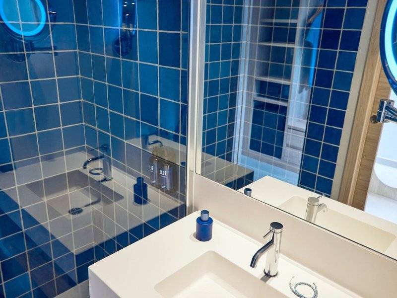 Badezimmer mit blauen Fliesen und einem Spiegel im Hotel Victoria Menorca.