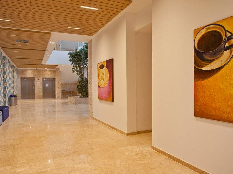 Der Flur des Seth 55 Santo Tomás Hotels mit Kunstwerken und einem Getränk auf dem Boden.