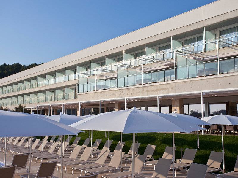 Außenbereich des Seth 55 Santo Tomás Hotels mit vielen weißen Sonnenschirmen und Sonnenliegen