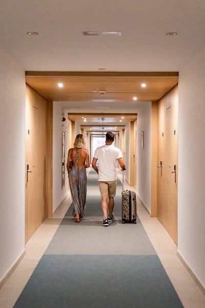 Ein Paar läuft mit Gepäck durch einen Hotelkorridor des Seth 55 Santo Tomás.