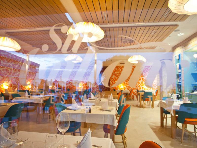 Innenansicht des Restaurants Seth 55 Santo Tomás mit blauen und orangefarbenen Stühlen und Tischen.