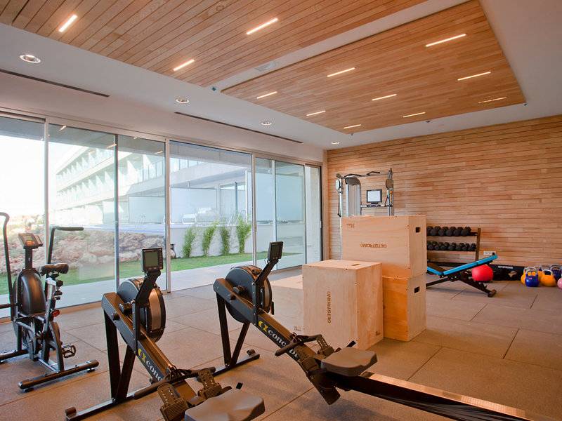 Fitnessraum im Hotel Seth 55 Santo Tomás mit Geräten und großen Fenstern.