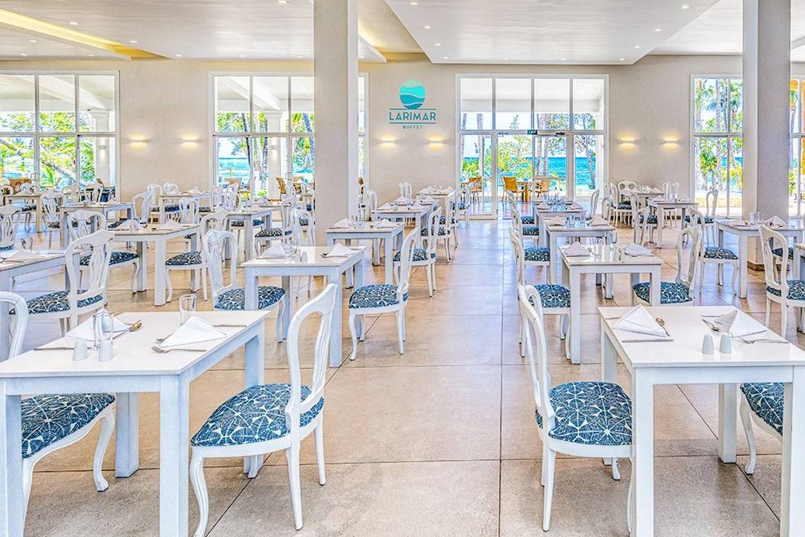 Innenansicht des Buffet-Restaurants im Senator Puerto Plata Spa Resort mit weißen Tischen und Stühlen, Blick auf das Meer.