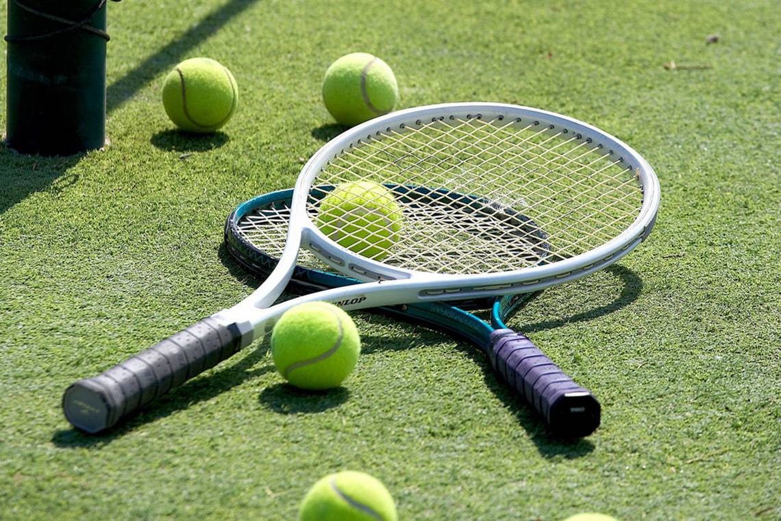 Tennisschläger und Tennisbälle auf grünem Kunstrasen