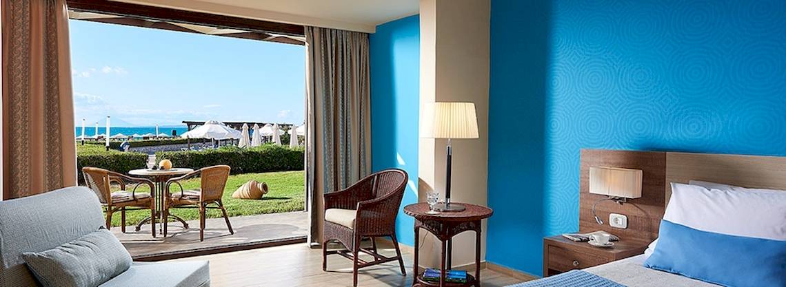 Ein modernes Hotelzimmer mit Blick auf das Meer, dekoriert mit blauen Wänden und einem kleinen Tisch mit einer Lampe.