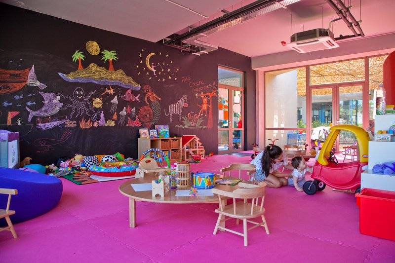 Kinderzimmer im Miraggio Thermal Spa Resort mit bunten Wänden, Spielsachen und einer Frau mit Kind.