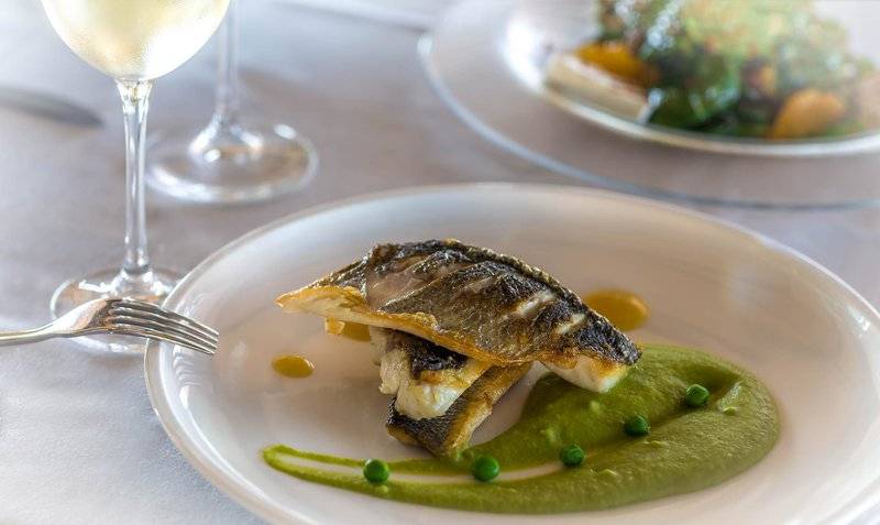 Fischgericht auf einem weißen Teller mit grüner Sauce und Erbsen, serviert im Miraggio Thermal Spa Resort.