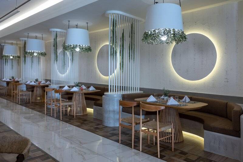 Innenbereich des Restaurants im Miraggio Thermal Spa Resort mit modernen Möbeln und dekorativen Pflanzen.