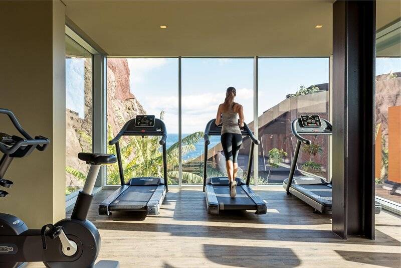 Frau im Fitnessraum des Saccharum Hotels, der Blick geht auf das Meer.