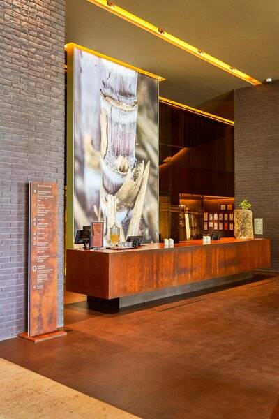 Empfangsbereich des Saccharum Hotels mit einer großen Wandkunst aus Bambus.