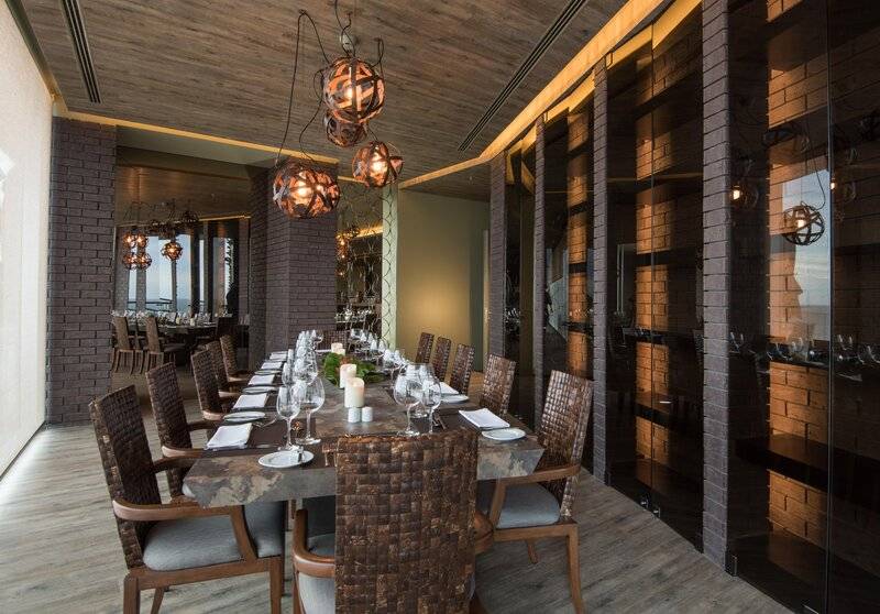 Innenansicht des Restaurants im Saccharum Hotel mit langen Tisch, Holzstühlen und modernen Kronleuchtern.