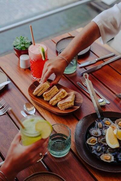 Gäste des Saccharum Hotels genießen ein Essen mit Getränken an einem Tisch.