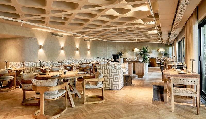 Innenbereich des Suite Hotel Eden Mar mit Holztischen, Stühlen und Pflanzen.