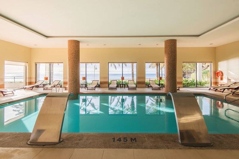 Poolbereich im Vila Galé Santa Cruz mit Blick auf den Strand und Sonnenliegen.