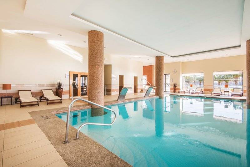 Innenpool des Vila Galé Santa Cruz Hotels mit Loungebereich und Treppen.