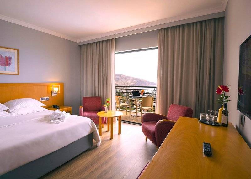Hotelzimmer mit komfortablem Bett, Möbeln und Terrasse mit Blick auf den Berg