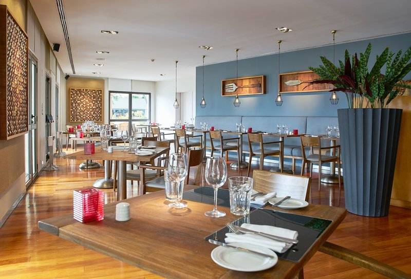 Innenansicht des Restaurants im Hotel Porto Mare - PortoBay mit blauen Wänden und Holzmöbeln.