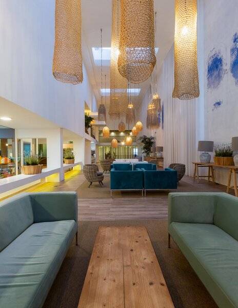 Innenbereich des Views Oasis Hotel mit hellem Design, blauen Sofas, Holztisch und hängenden Lampen.