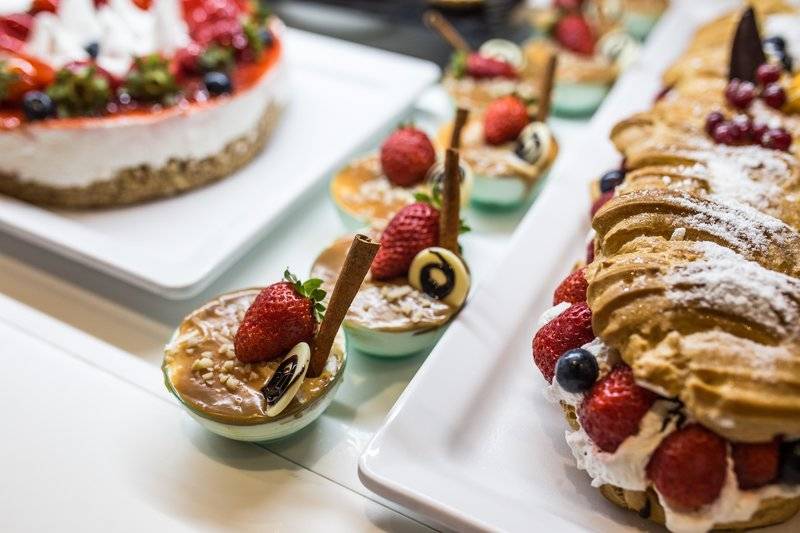 Desserts im The Views Oasis Hotel, darunter Kuchen und Gebäck mit Früchten und Schokolade.