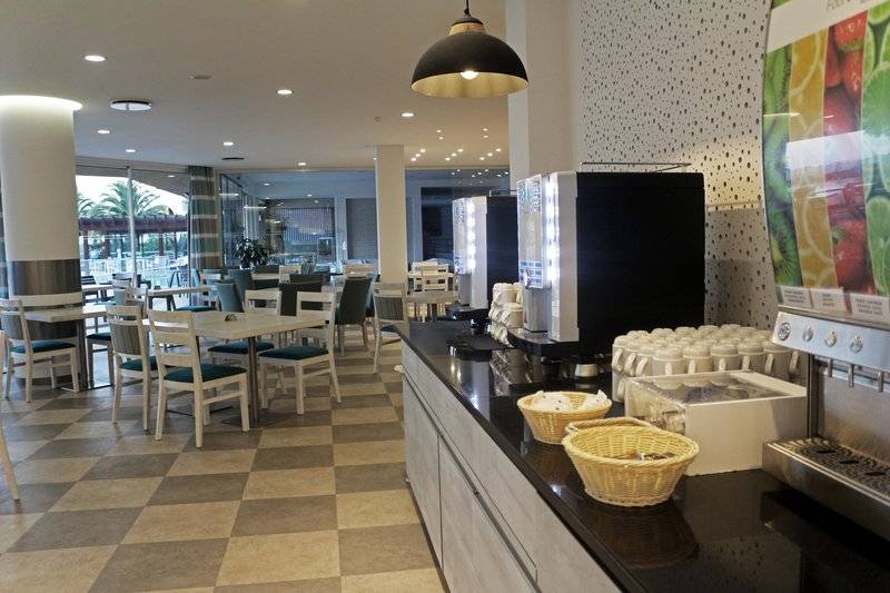 Frühstücksbereich im Views Oasis Hotel mit Tischen, Stühlen und Kaffeemaschinen.