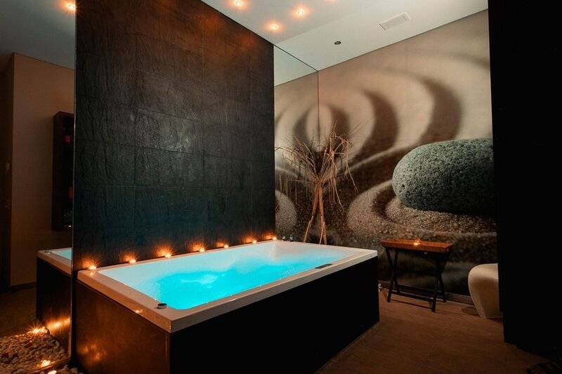 Spa-Badewanne im Views Oasis Hotel mit blauem Wasser und dekorativen Steinen.