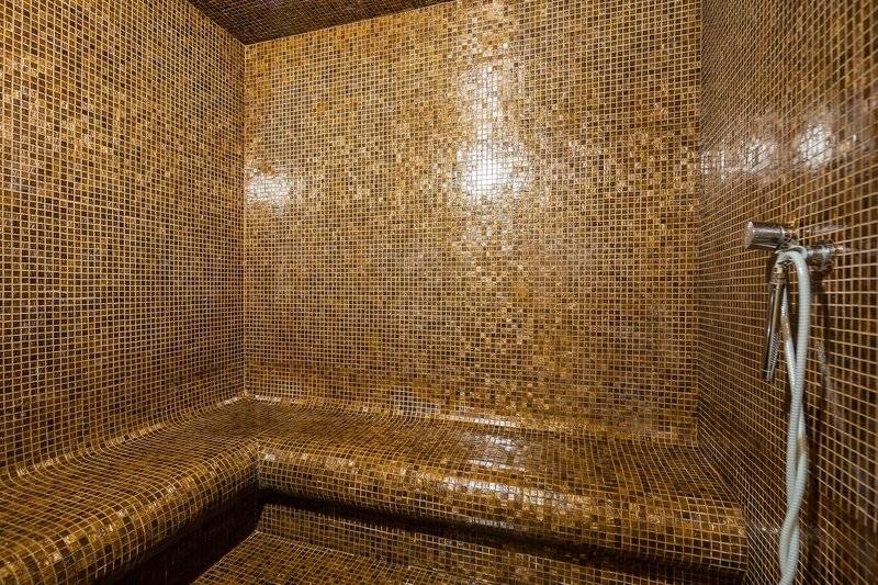 Saunabereich im Views Oasis Hotel mit goldenen Mosaikfliesen und einer Dusche.