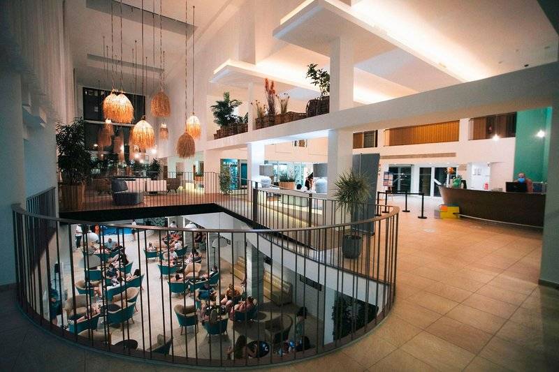 Innenansicht des The Views Oasis Hotel mit mehreren Stockwerken, Sitzbereichen und Pflanzen.