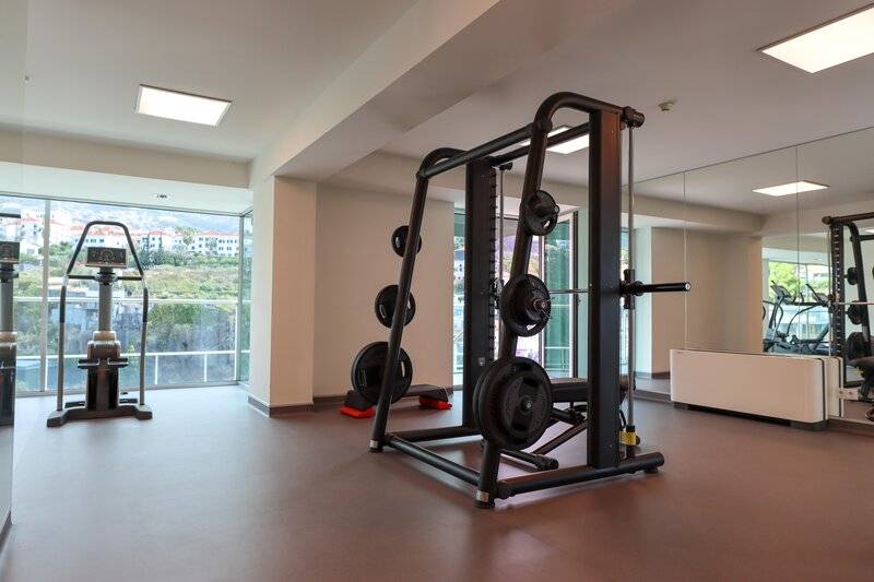 Fitnessstudio im The Views Baia Hotel mit Geräten und Ausblick auf die Stadt.