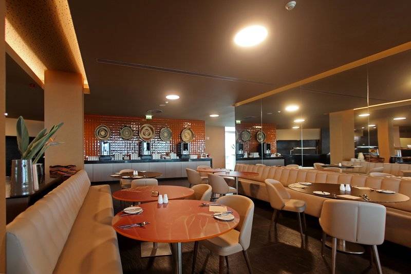 Innenansicht des Frühstücksraums im Hotel Views Baia mit runden Tischen und Sitzbänken.