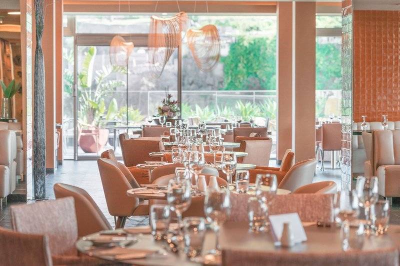 Innenansicht des The Views Baia Restaurants mit runden Tischen, Gläsern und modernen Lampen.