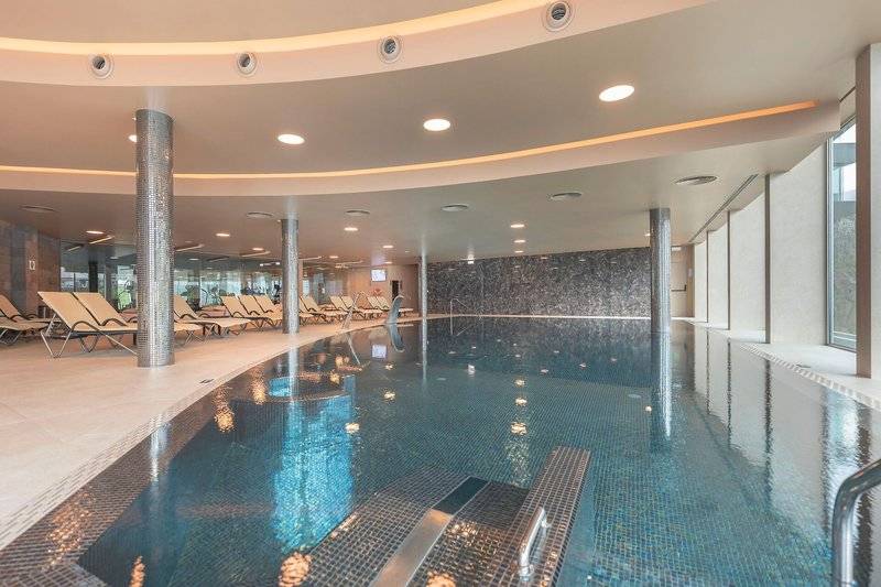 Innenpool des Hotels The Views Baia mit Loungeliegen und blauem Wasser