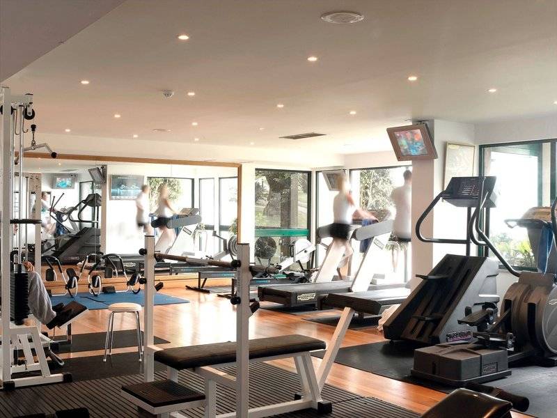 Fitnessbereich im The Cliff Bay Hotel mit verschiedenen Geräten und Menschen, die trainieren.